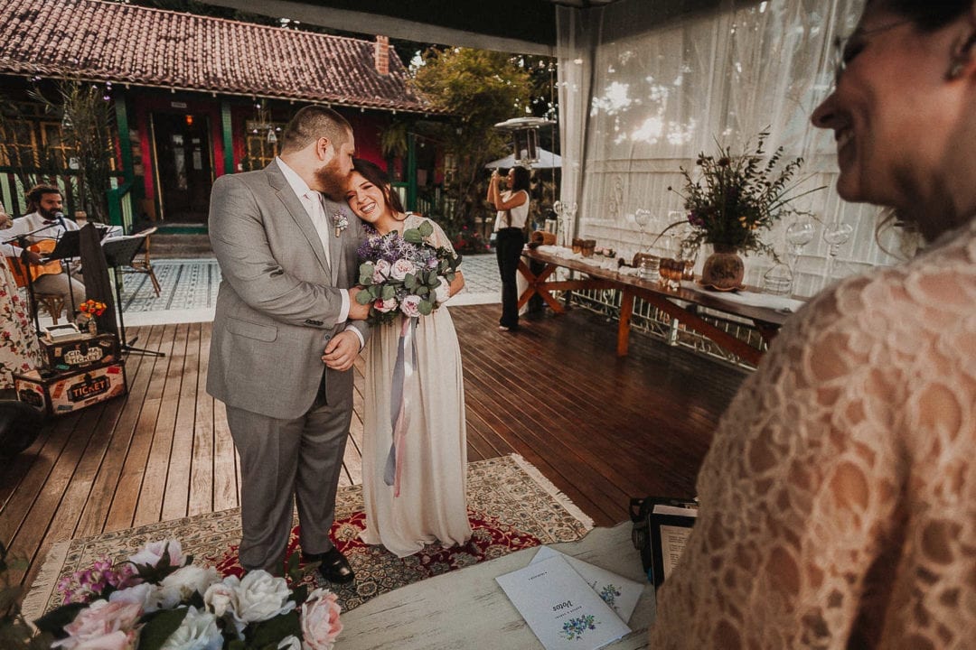Noivo dando um beijo na testa da noiva que está com a cabeça apoiada em seu ombro, durante a cerimonia de elopement.