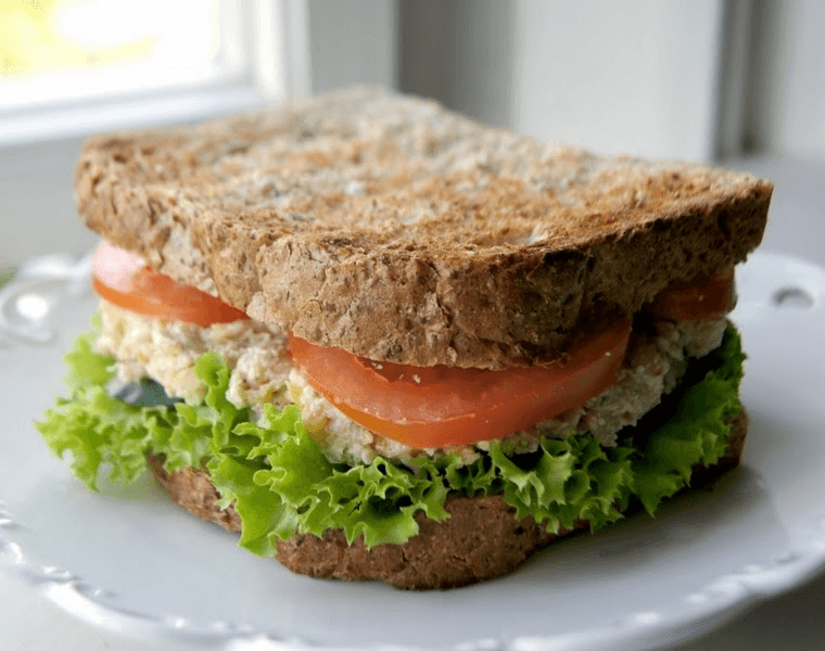 Lanche integral de frango, com alface, rúcula e tomate.