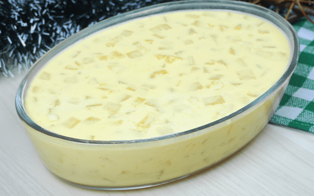 gelado de abacaxi, uma sobremesa numa travessa de vidro transparente. A sobremesa é amarelada com pedaços pequenos de abacaxi nela