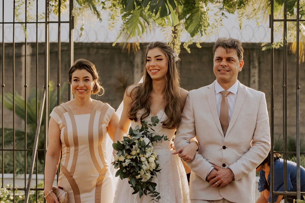 noiva entrando com os pais na cerimônia no campo