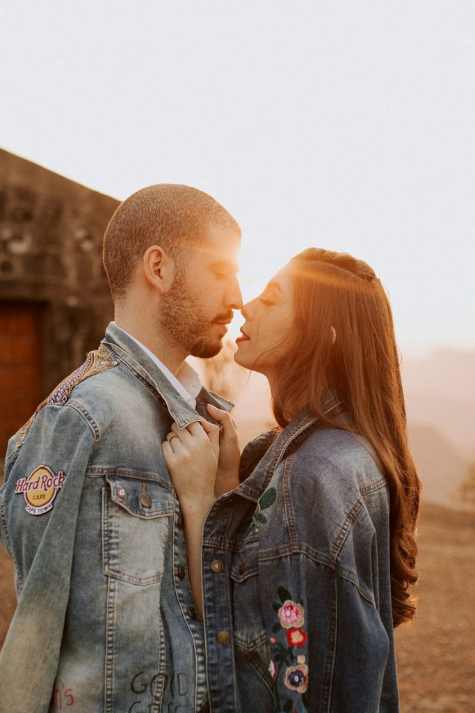 noivos posam no pôr do sol, a noiva usa uma jaqueta e um buquê de folhas secas - fotos pós wedding