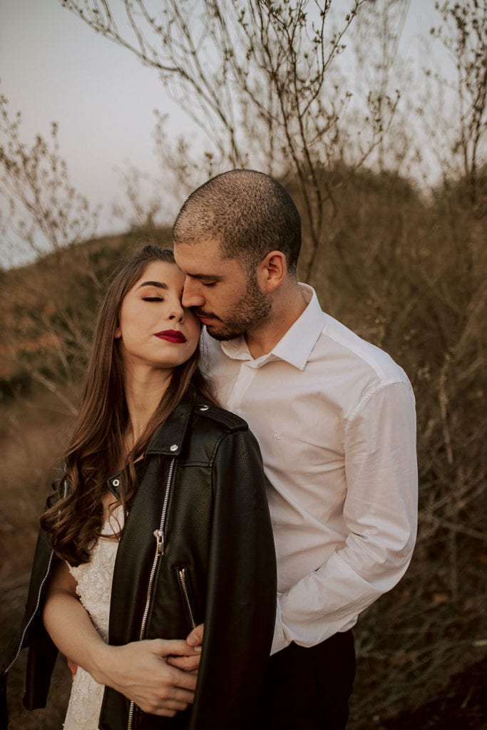 noivos posam no pôr do sol, a noiva usa uma jaqueta e um buquê de folhas secas - fotos pós wedding
